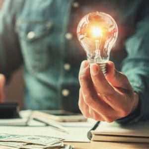 Person holding a lit lightbulb symbolizing fire damage testing and innovation.